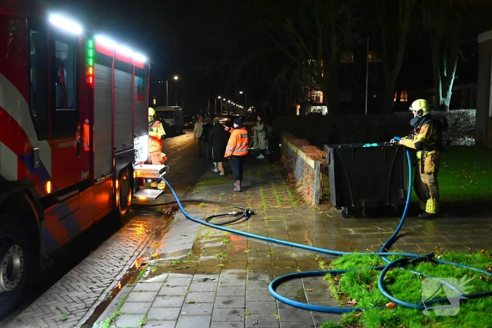 Brandweer blust brand in vuilcontainer