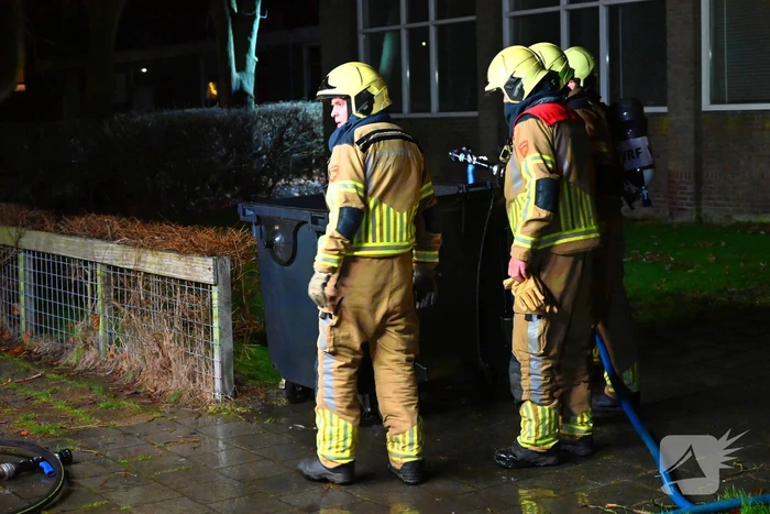 Brandweer blust brand in vuilcontainer