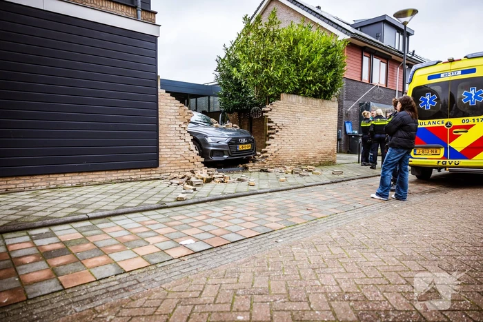 Auto rijdt dwars door tuinmuur
