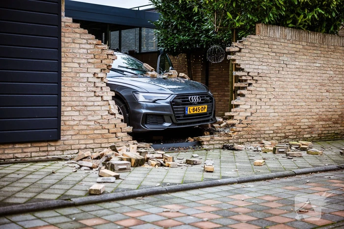 Auto rijdt dwars door tuinmuur
