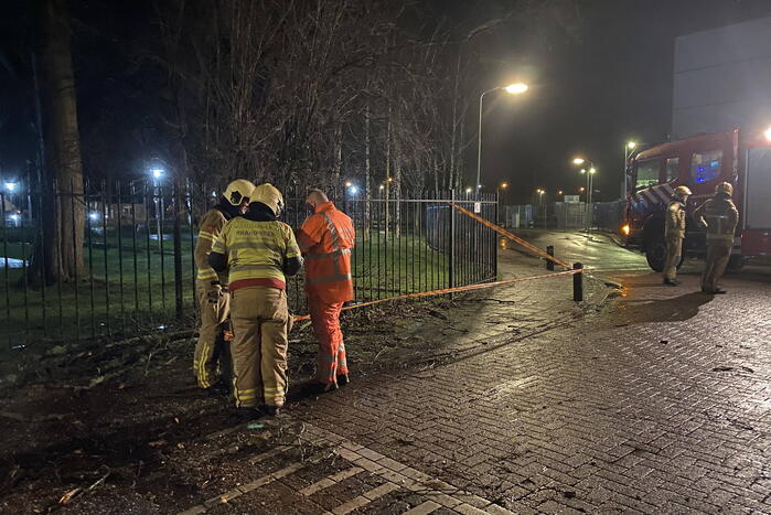 Omgevallen boom valt op hekwerk en blokkeert weg