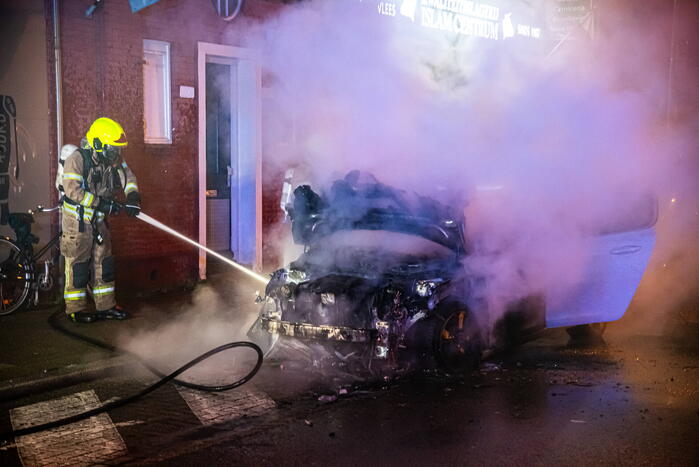 Brandweer blust in brand staande auto