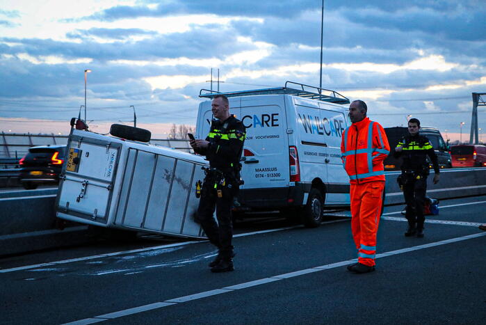 Bestelbus met aanhanger belandt op zijkant