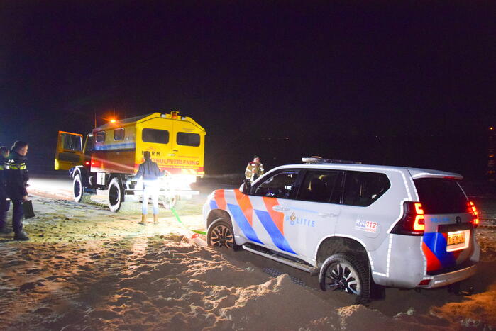 Politiejeep muurvast in los zand op strand