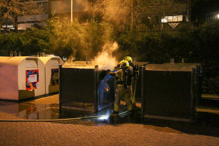 Brandweer blust brandende papiercontainer