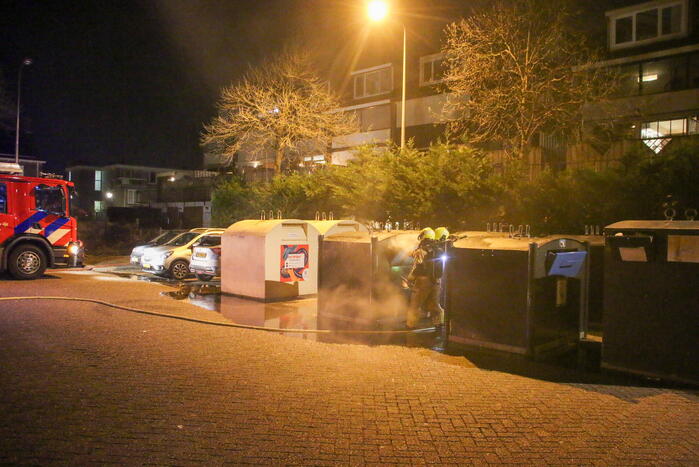 Brandweer blust brandende papiercontainer
