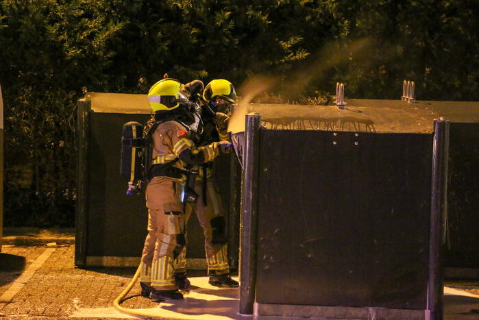 Brandweer blust brandende papiercontainer