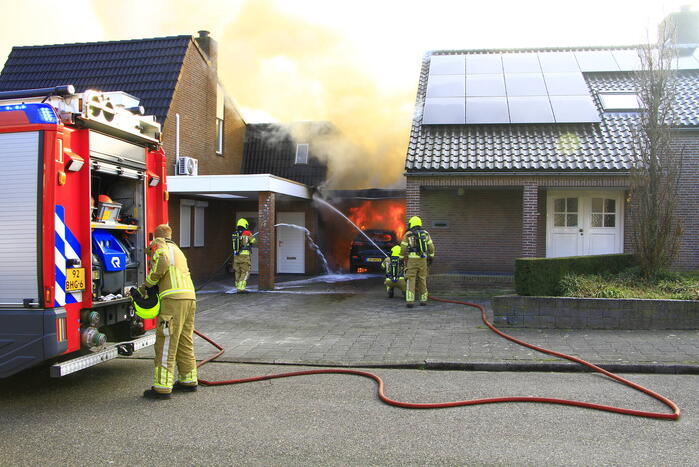 Personenauto vat vlam onder carport