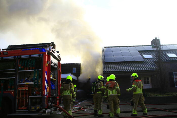 Personenauto vat vlam onder carport