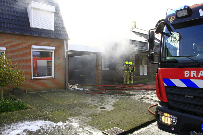 Personenauto vat vlam onder carport