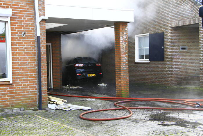 Personenauto vat vlam onder carport