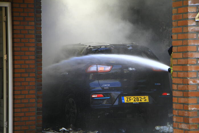 Personenauto vat vlam onder carport