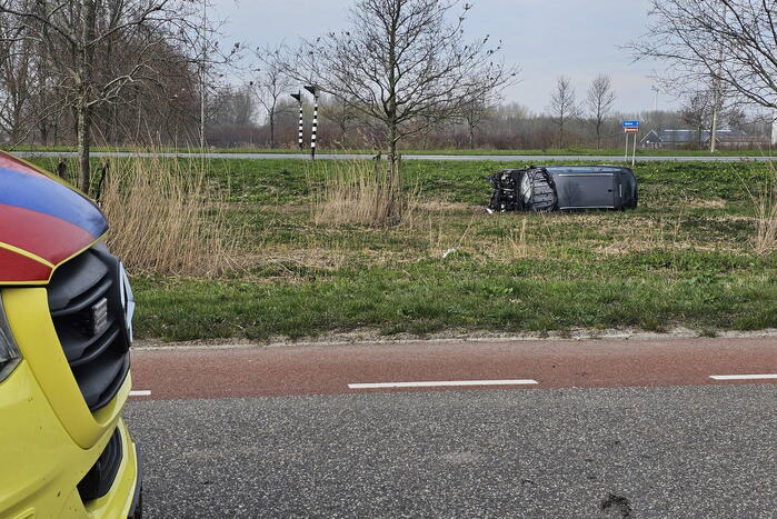 Auto ramt verkeerslicht en belandt op zijn zij in een greppel