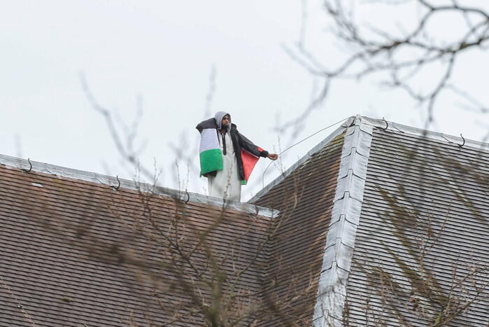 Demonstrant klimt op gebouw naast gemeentehuis