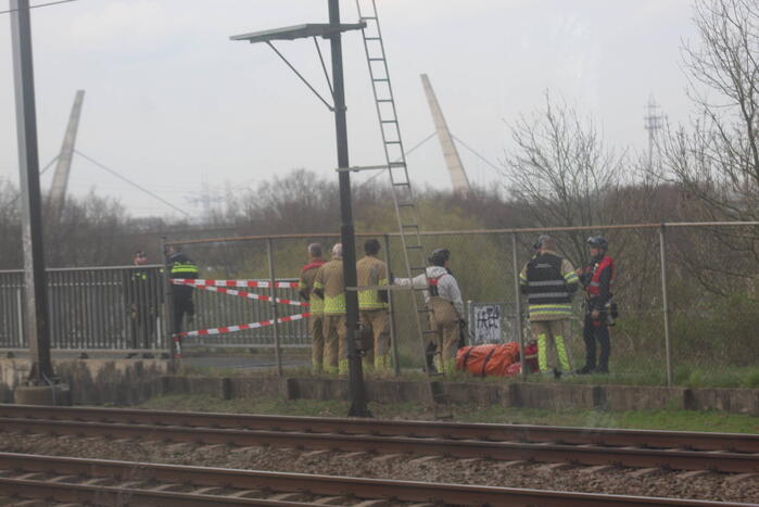 Persoon op bogen van brug, vele hulpdiensten aanwezig