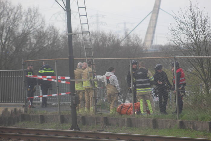 Persoon op bogen van brug, vele hulpdiensten aanwezig