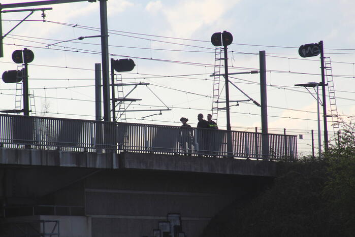 Persoon op bogen van brug, vele hulpdiensten aanwezig