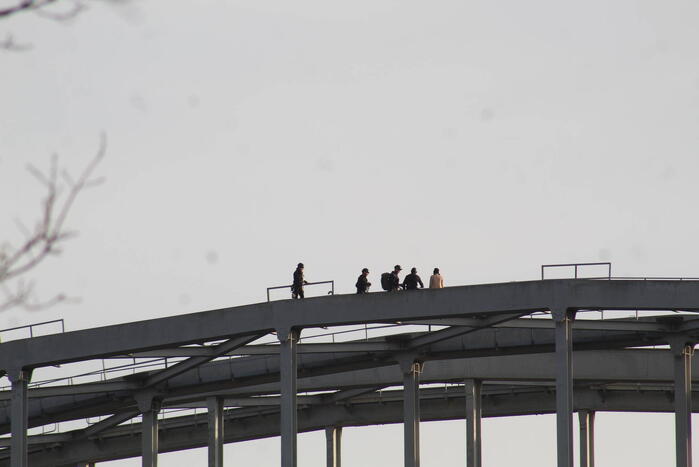 Persoon op bogen van brug, vele hulpdiensten aanwezig