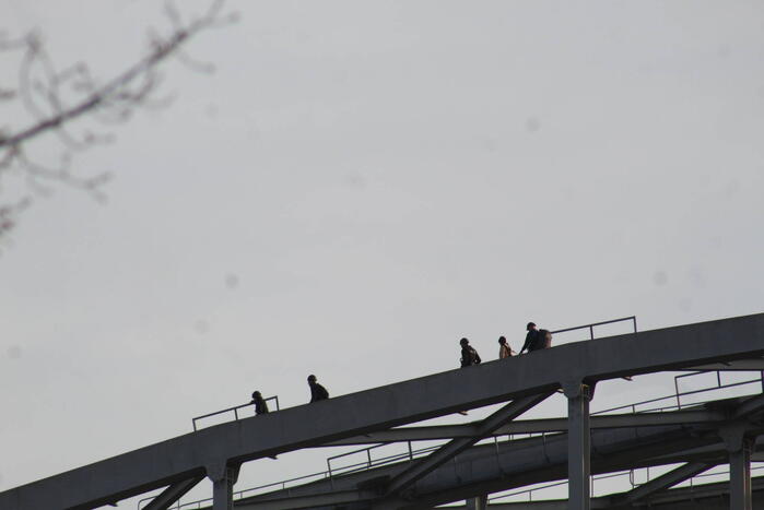 Persoon op bogen van brug, vele hulpdiensten aanwezig