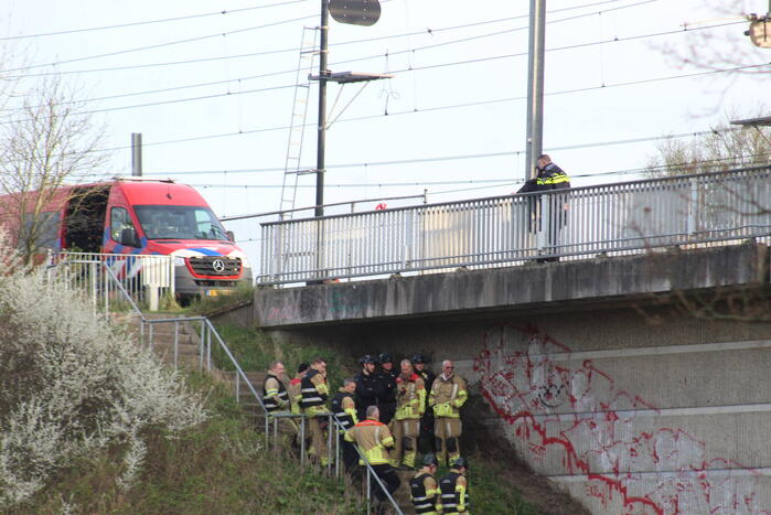 Persoon op bogen van brug, vele hulpdiensten aanwezig