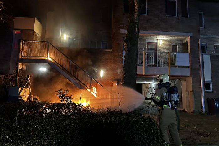 Brandweer blust brandende container onder trap