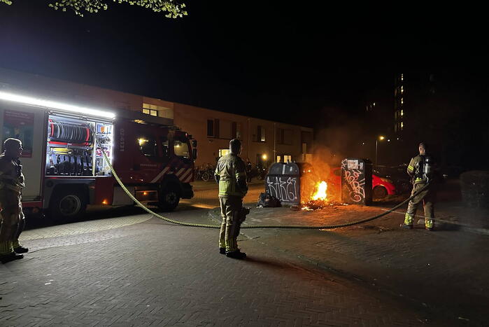 Brandweer blust brandend afval naast container