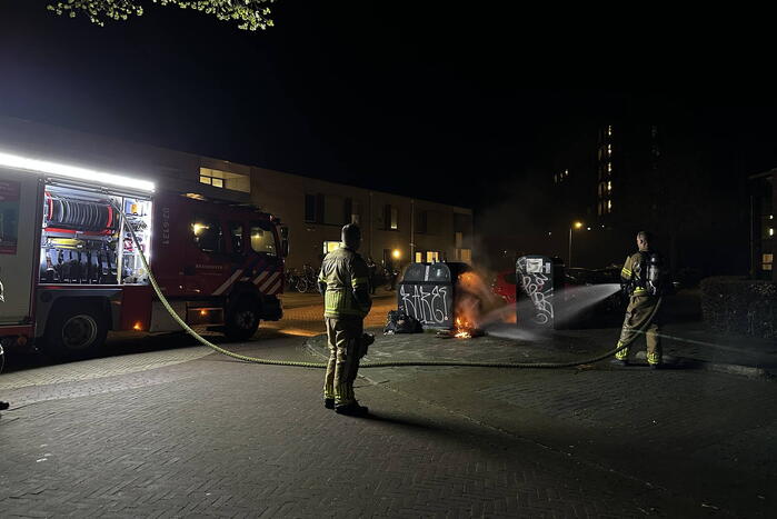 Brandweer blust brandend afval naast container