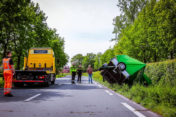 Aanhanger geladen met stenen belandt op zijn kant