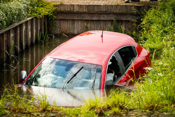 Omstanders helpen personen uit auto die te water raakte