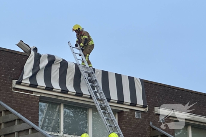 Zonnescherm waait kapot, brandweer ingezet