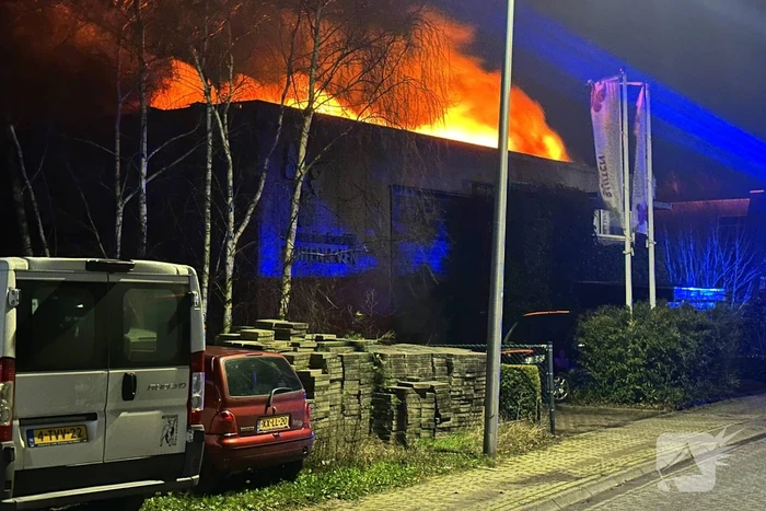 Vlammen slaan uit dak van gebouw