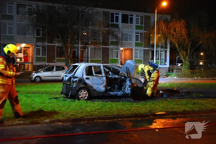 Auto in brand gestoken op grasveld