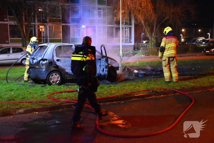 Auto in brand gestoken op grasveld