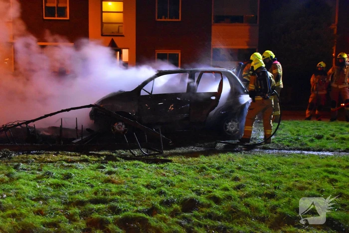 Auto in brand gestoken op grasveld