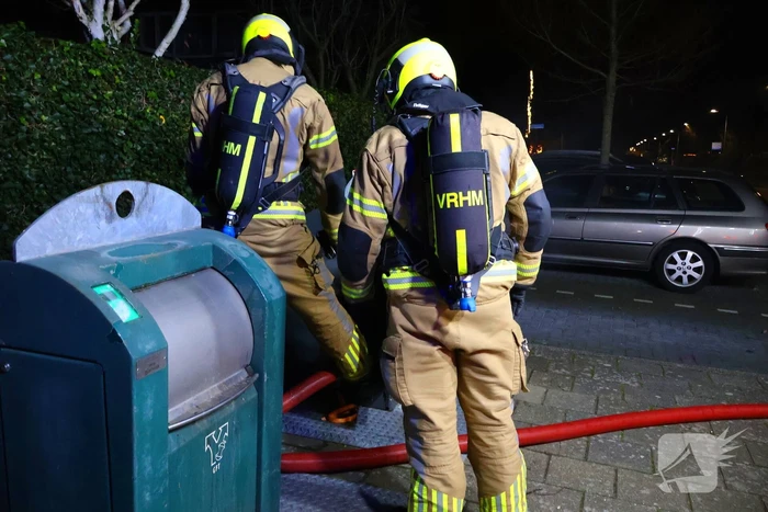Personen verrichten bluspoging bij containerbrand