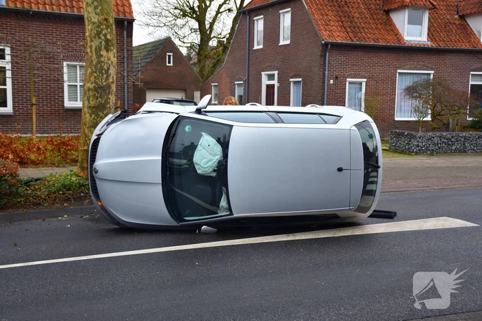 Bestuurster raakt boom, auto belandt op zijkant