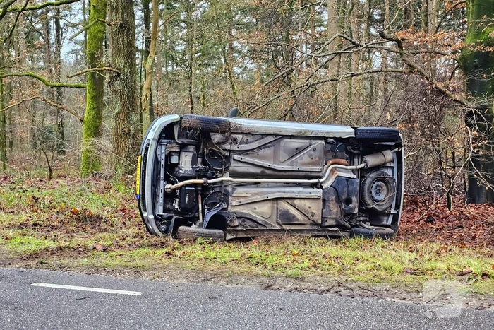 Auto belandt op zijkant naast weg
