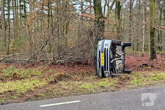 Auto belandt op zijkant naast weg