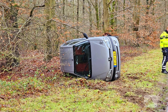 Auto belandt op zijkant naast weg