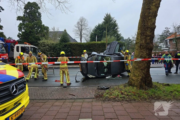 Auto belandt op zijn kant na botsing tegen boom