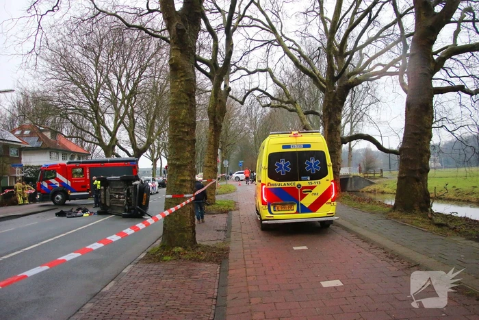 Auto belandt op zijn kant na botsing tegen boom