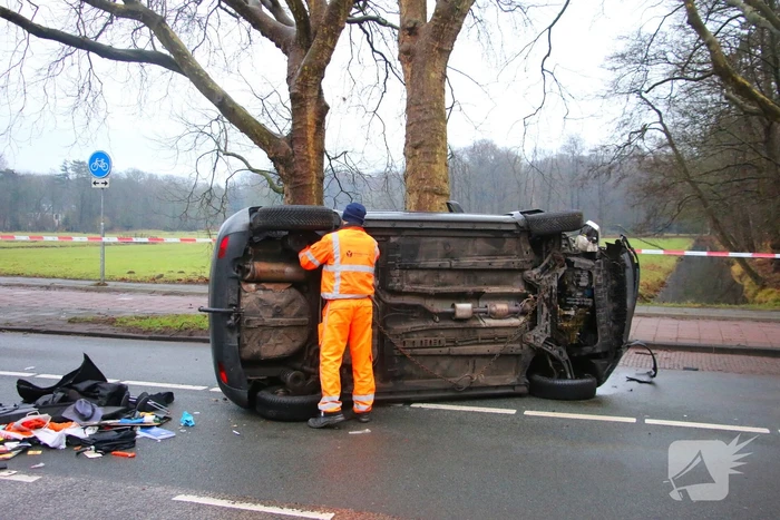 Auto belandt op zijn kant na botsing tegen boom