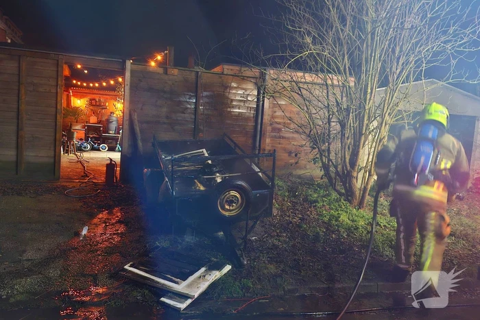Vlammen slaan uit aanhanger, buurtbewoner start blussing