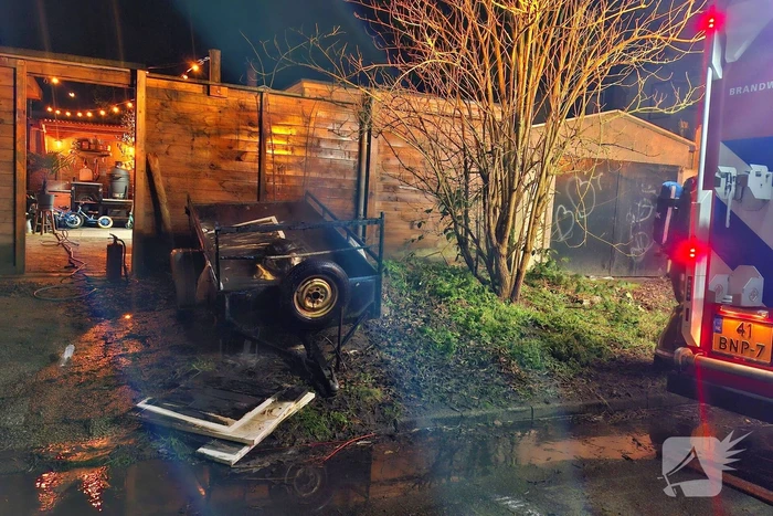 Vlammen slaan uit aanhanger, buurtbewoner start blussing