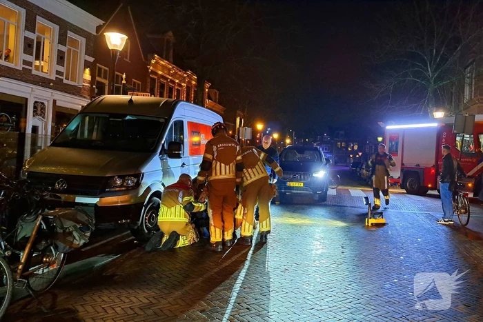 Persoon bekneld onder bestelbus