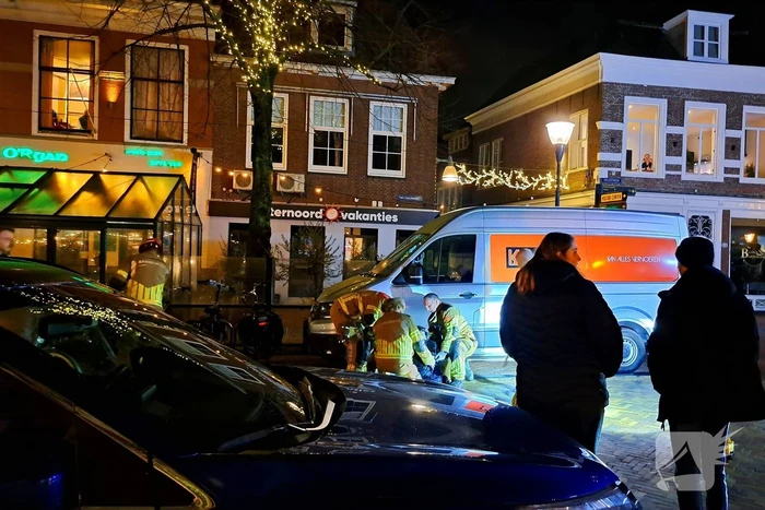 Persoon bekneld onder bestelbus