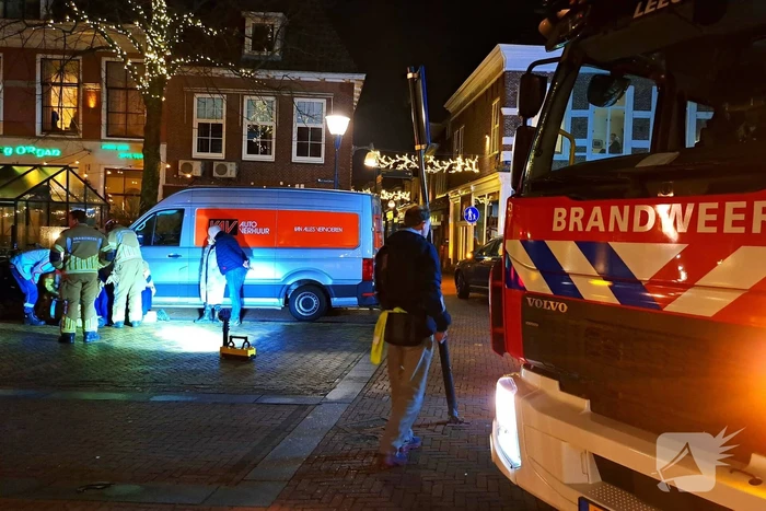 Persoon bekneld onder bestelbus