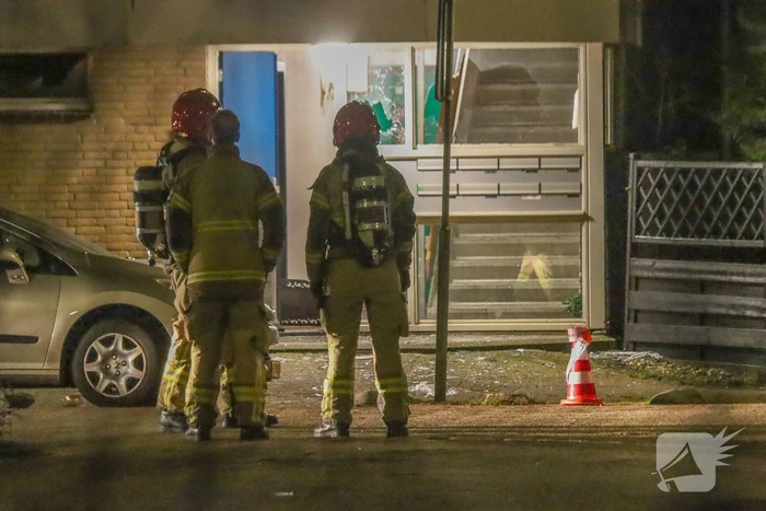 Explosie bij portiek van flatgebouw, brandweer blust vuurhaard