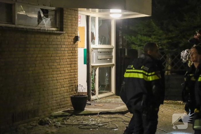 Explosie bij portiek van flatgebouw, brandweer blust vuurhaard