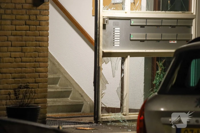 Explosie bij portiek van flatgebouw, brandweer blust vuurhaard